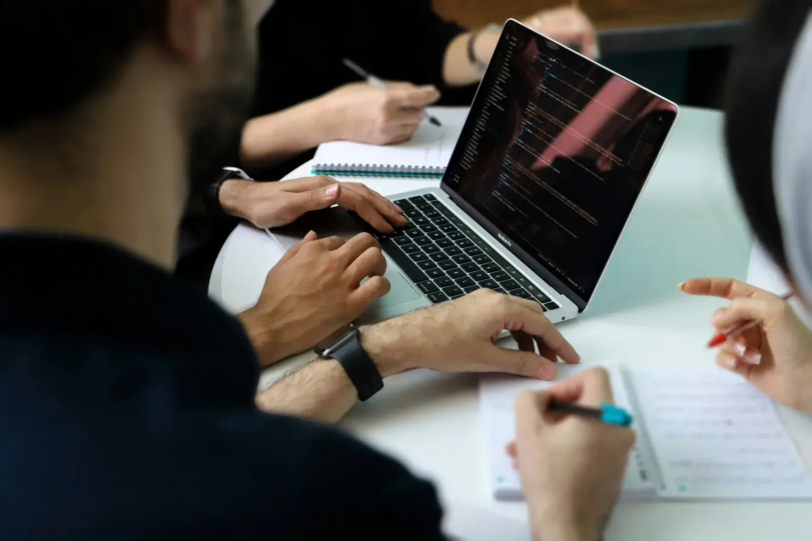 Close-up of laptop and people's hands at a workshop table